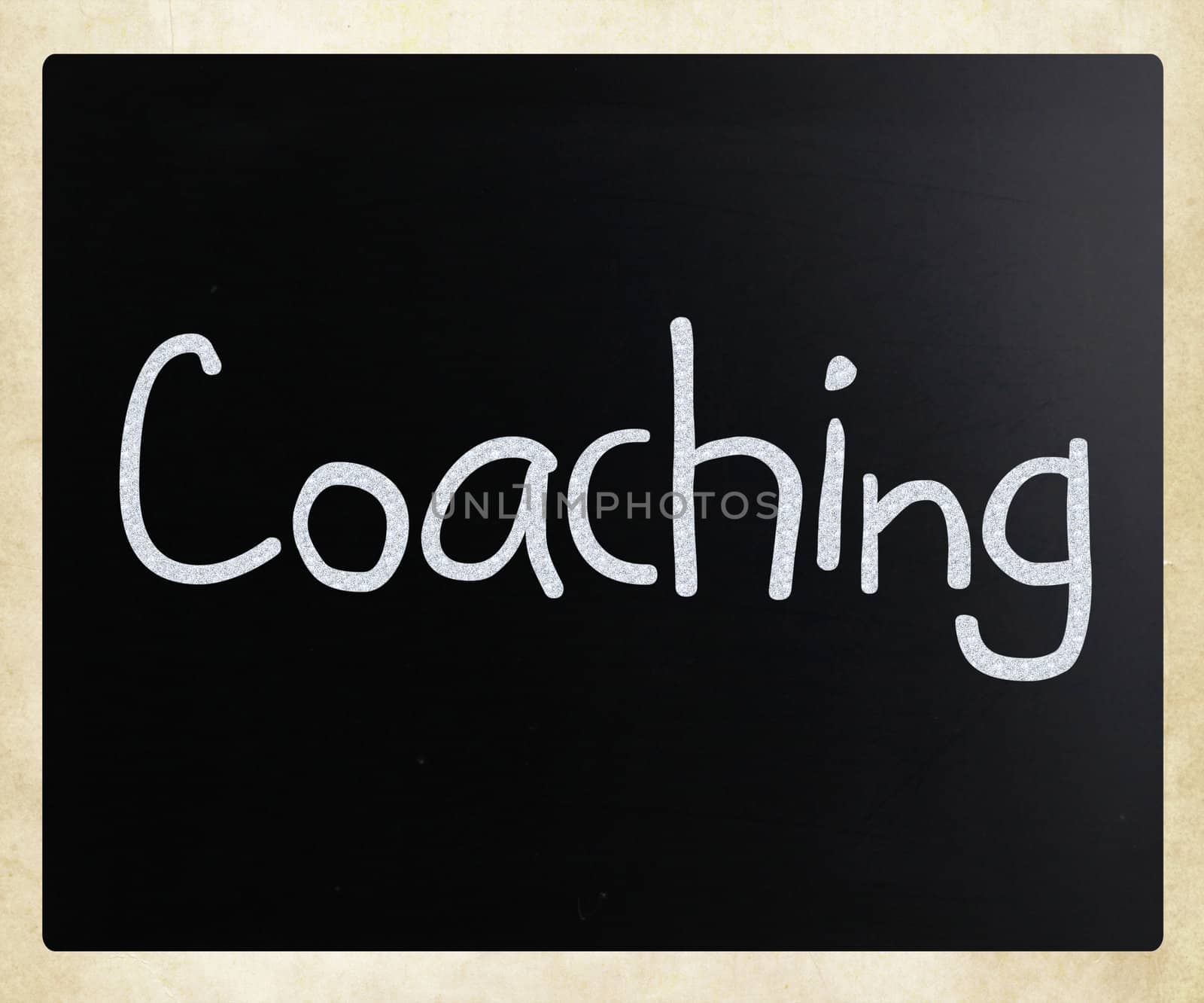 "Coaching" handwritten with white chalk on a blackboard