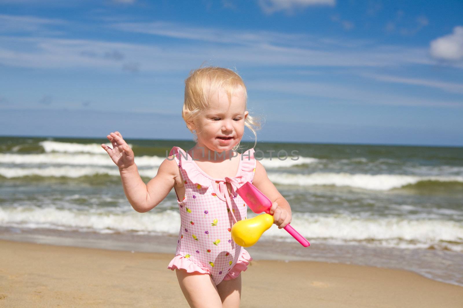small girl with toys on the seashore