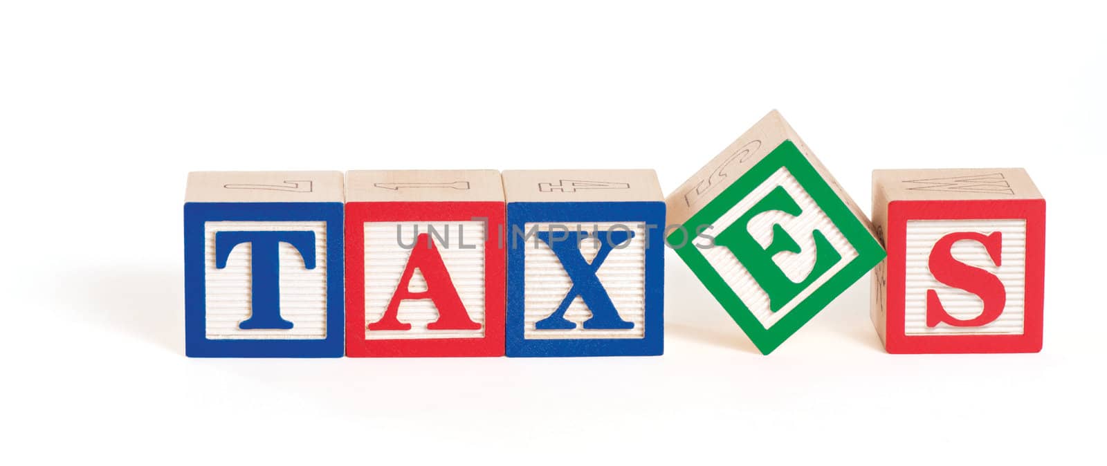Alphabet blocks arranged to spell the word, "taxes" with the letter 'E' askew. Isolated on white with clipping path.
