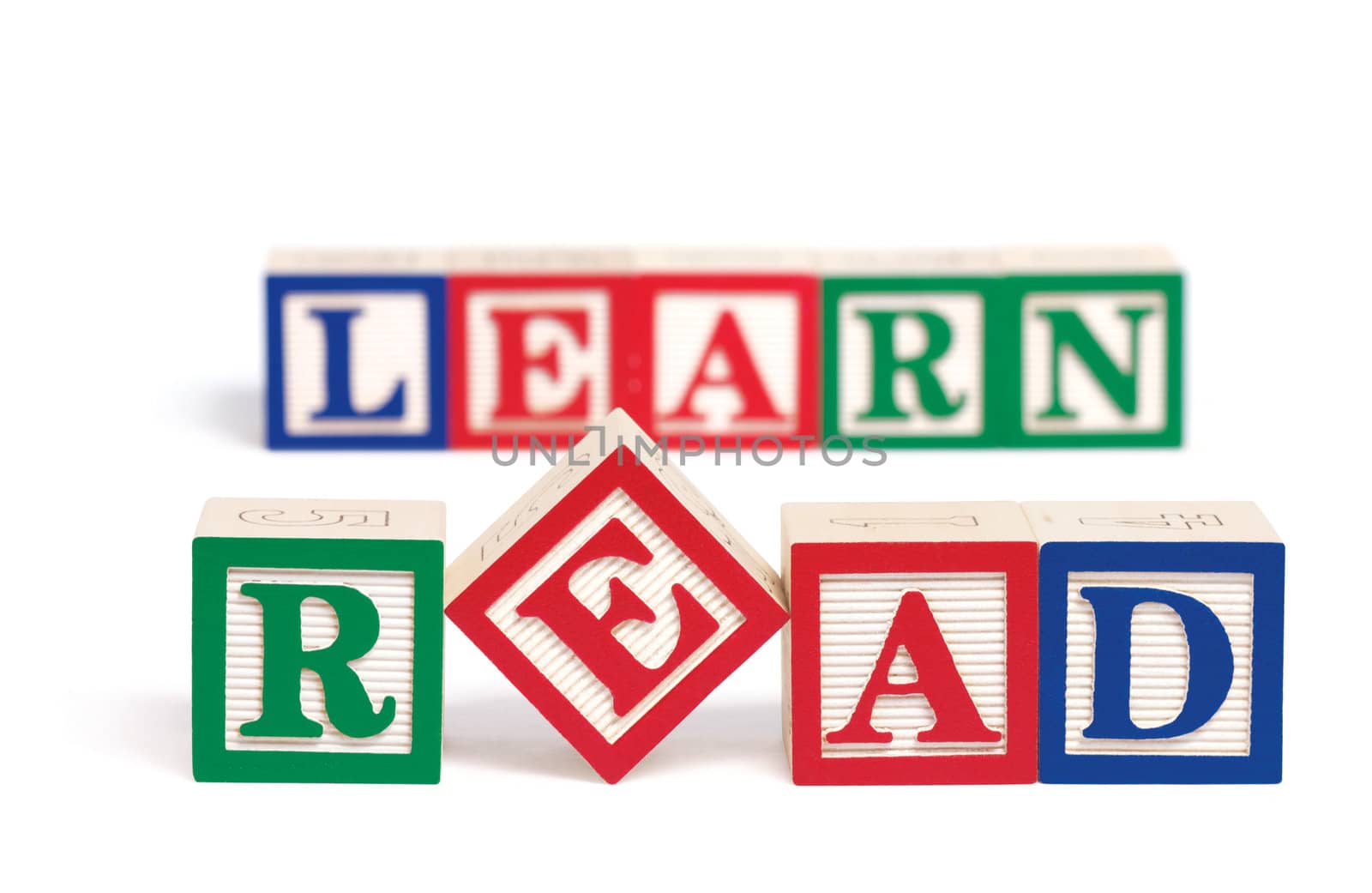Alphabet blocks spelling the word, "read." Behind them and slightly out of focus are alphabet blocks spelling the word, "learn." Isolated on white.