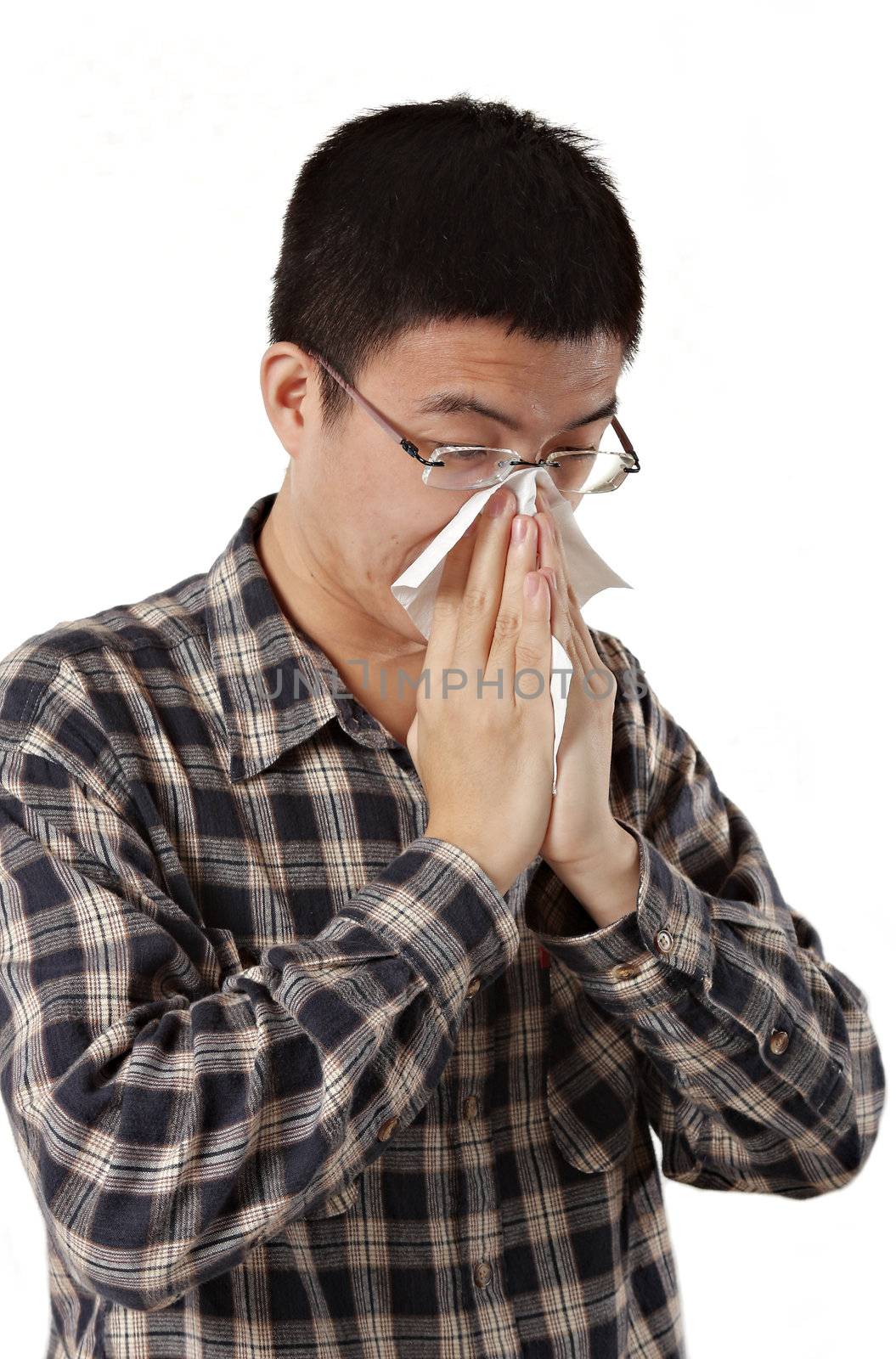 Young man with a cold blowing nose on tissue 