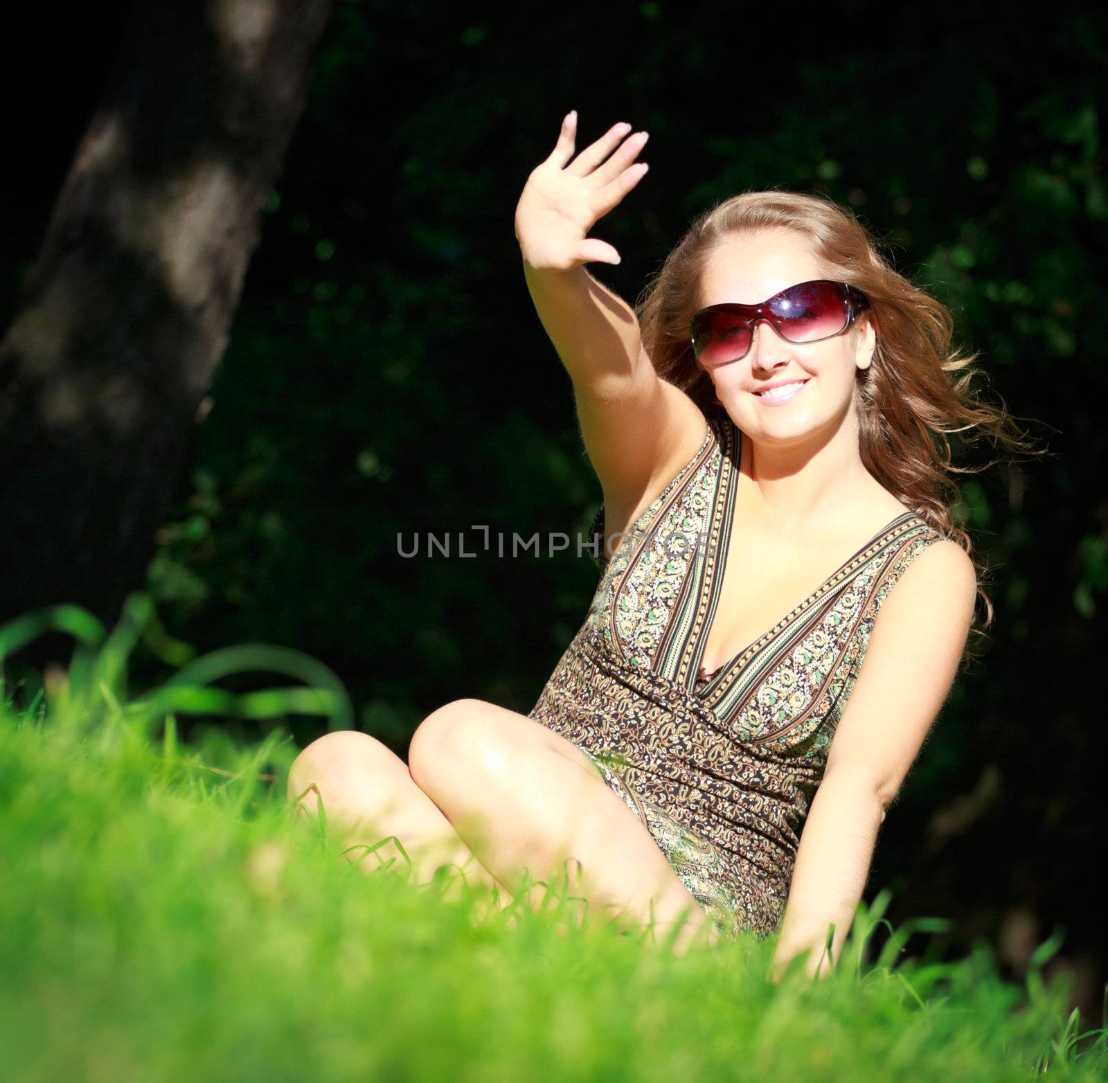 beautiful girl in sunglasses sitting in grass