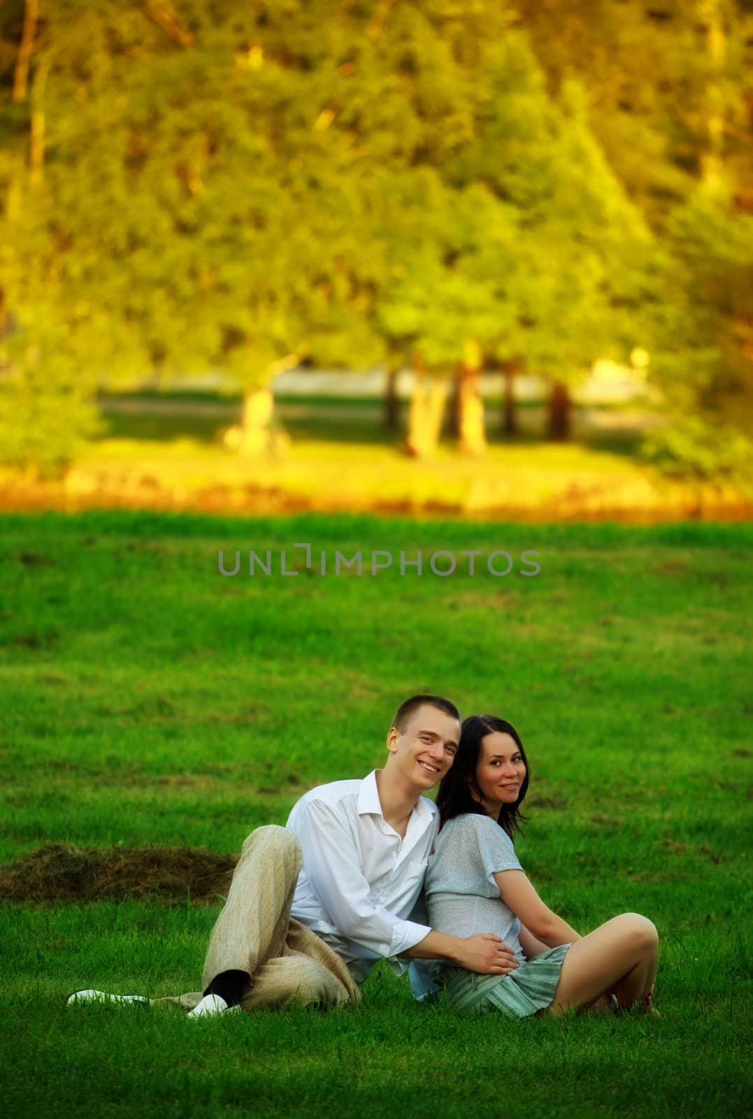 happy couple sitting on park lawn