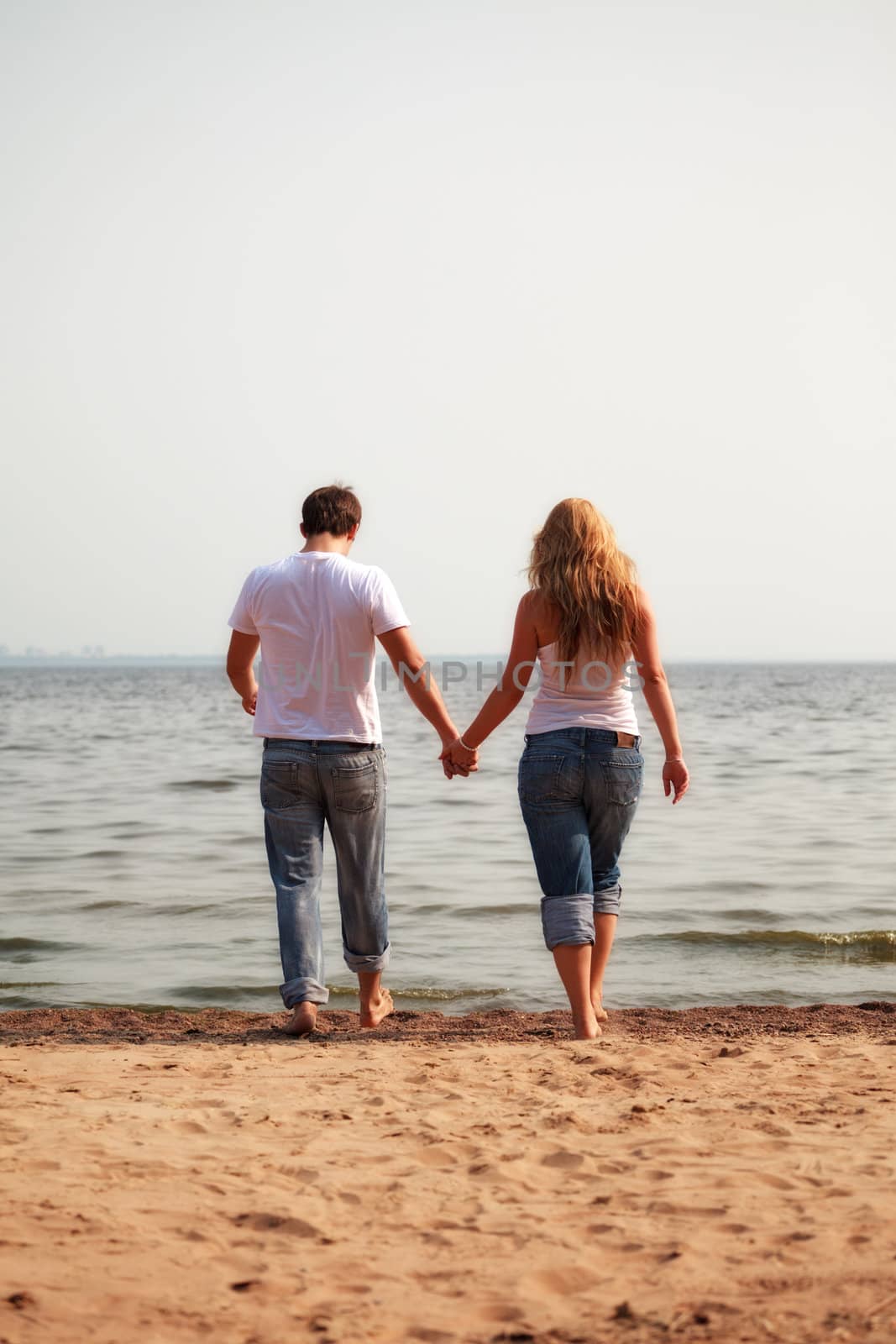 couple walking on a beach by petr_malyshev