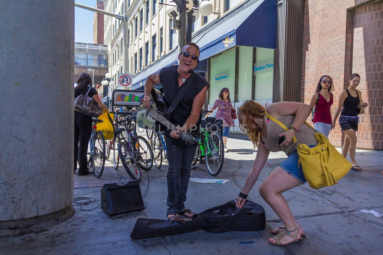 Musician that is playing guitar and sings is collecting money in Ottawa, Ontario, Canada