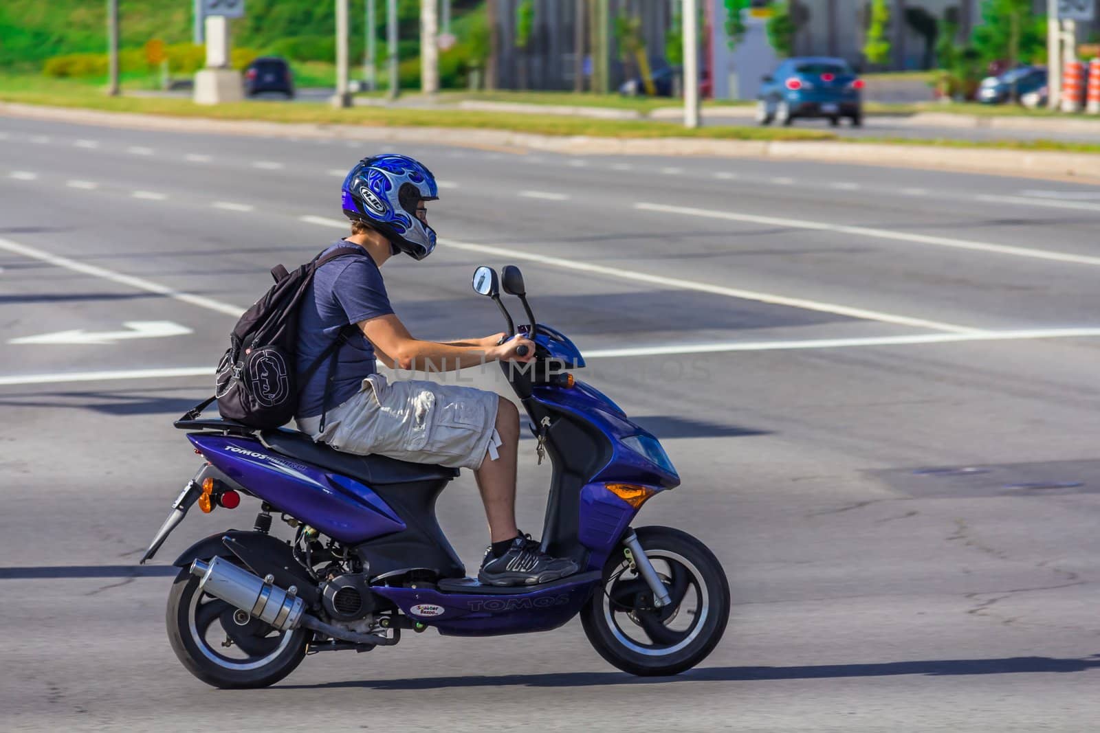 Man driving on low speed on a Tomos Nitro scooter in Taschereau street, Brossard, Quebec, Canada