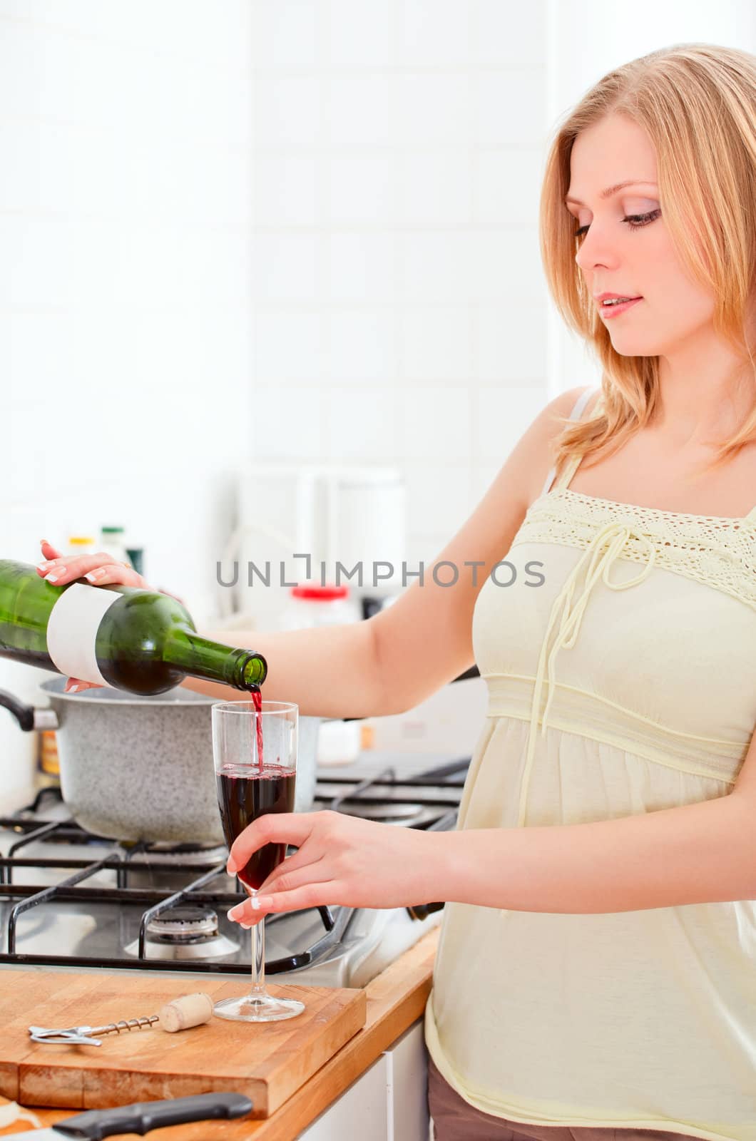 cute young woman pouring wine in kitchen