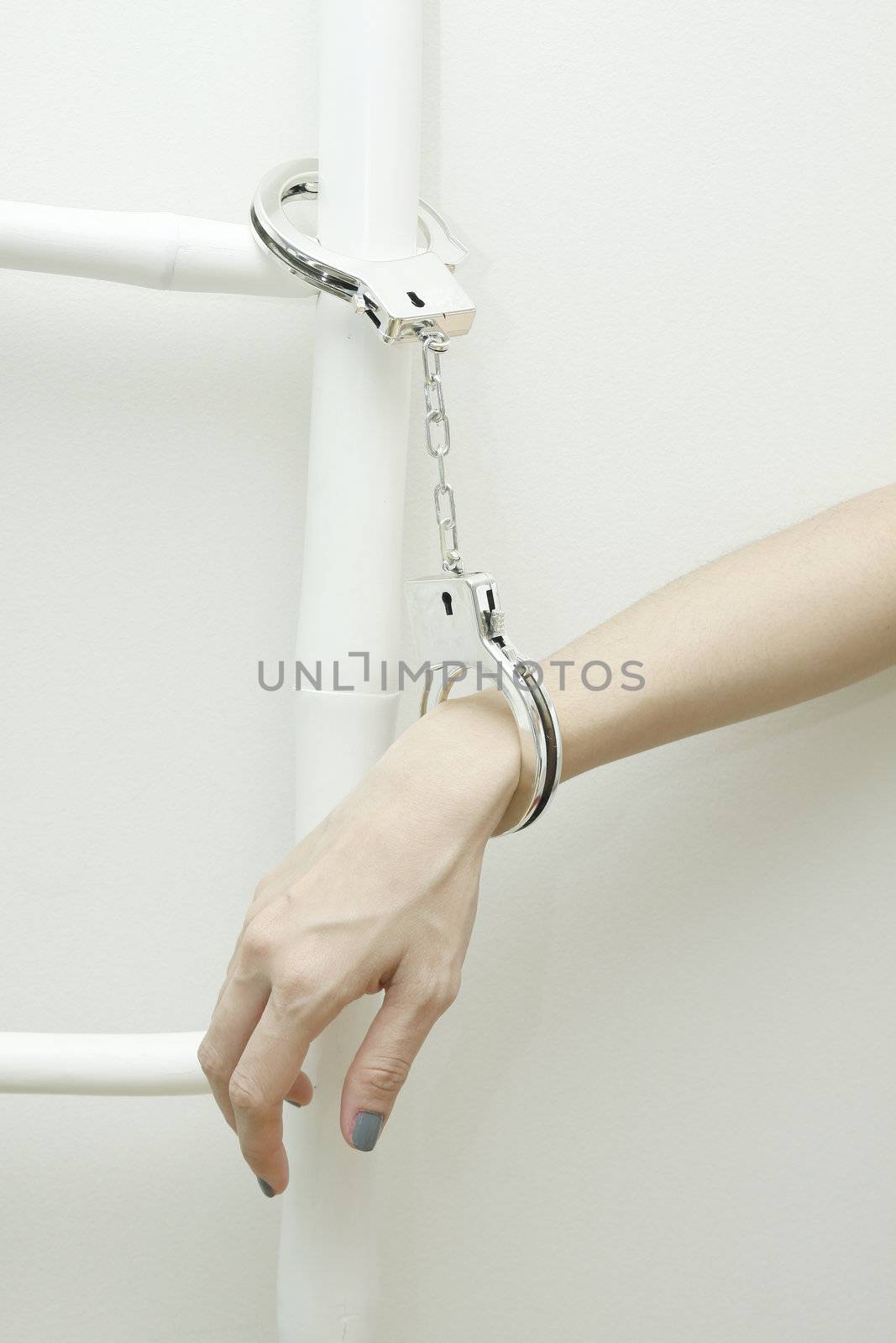 Woman right hand with handcuffs on white wall