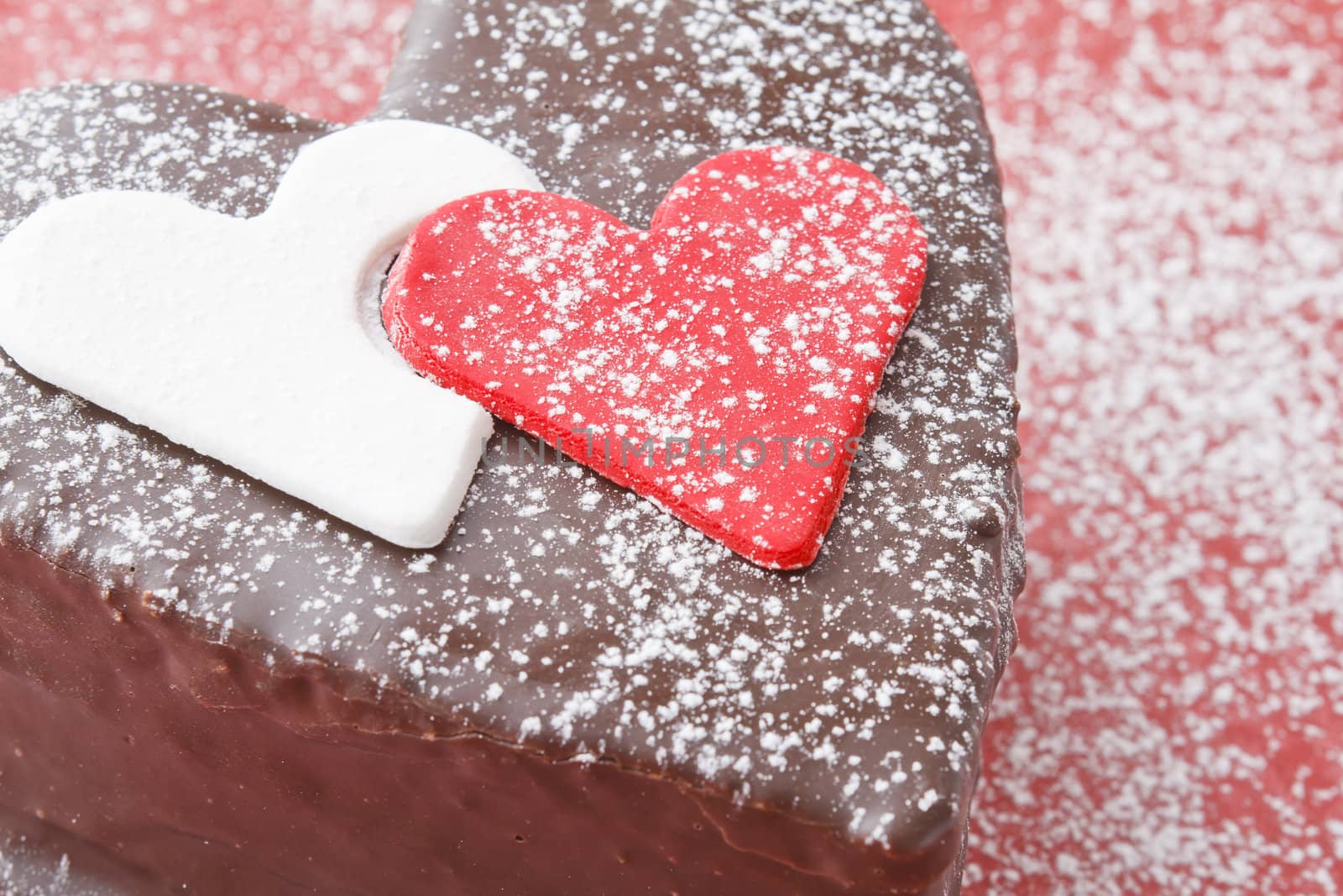 Heart shaped slice of a chocolate-cake on red background