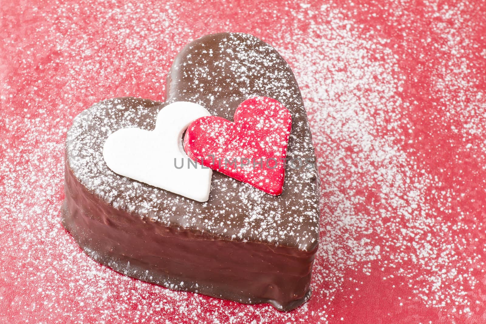 Heart shaped slice of a chocolate-cake on red background