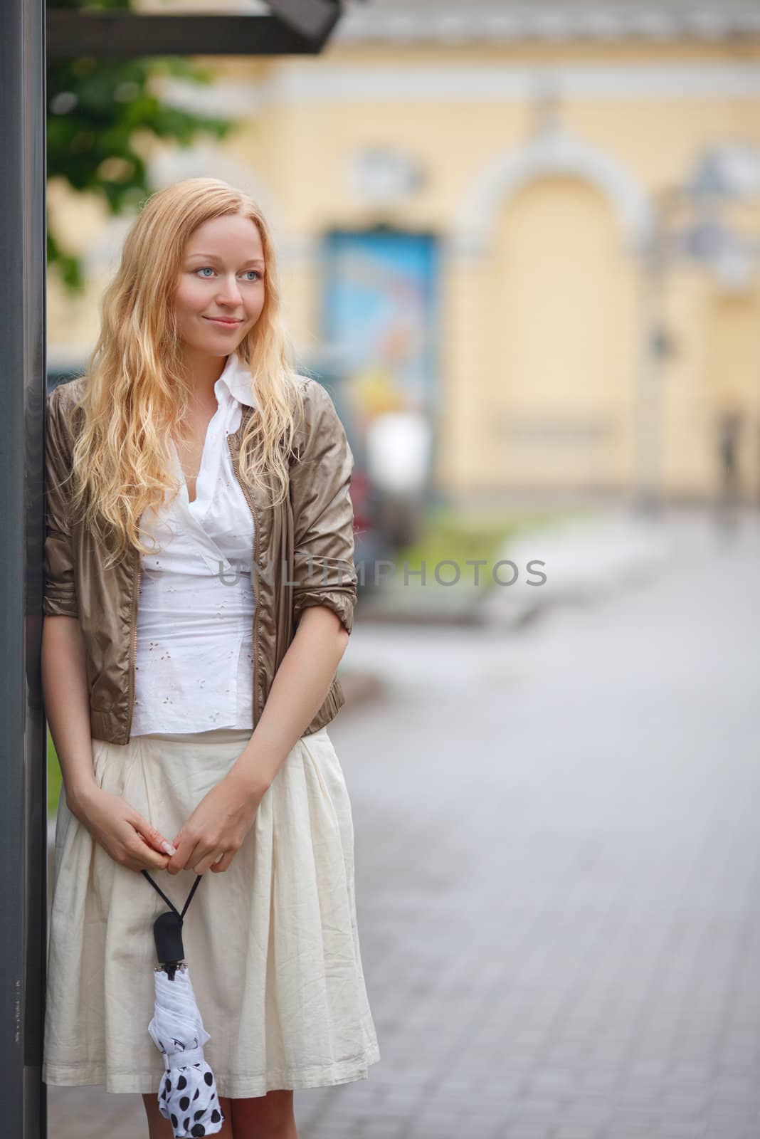 beautiful girl with umbrella near bus stop at rainy day