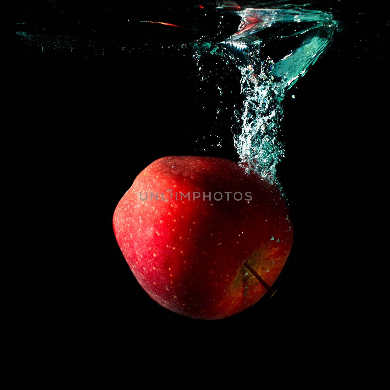 apple falling to water with splash over black background