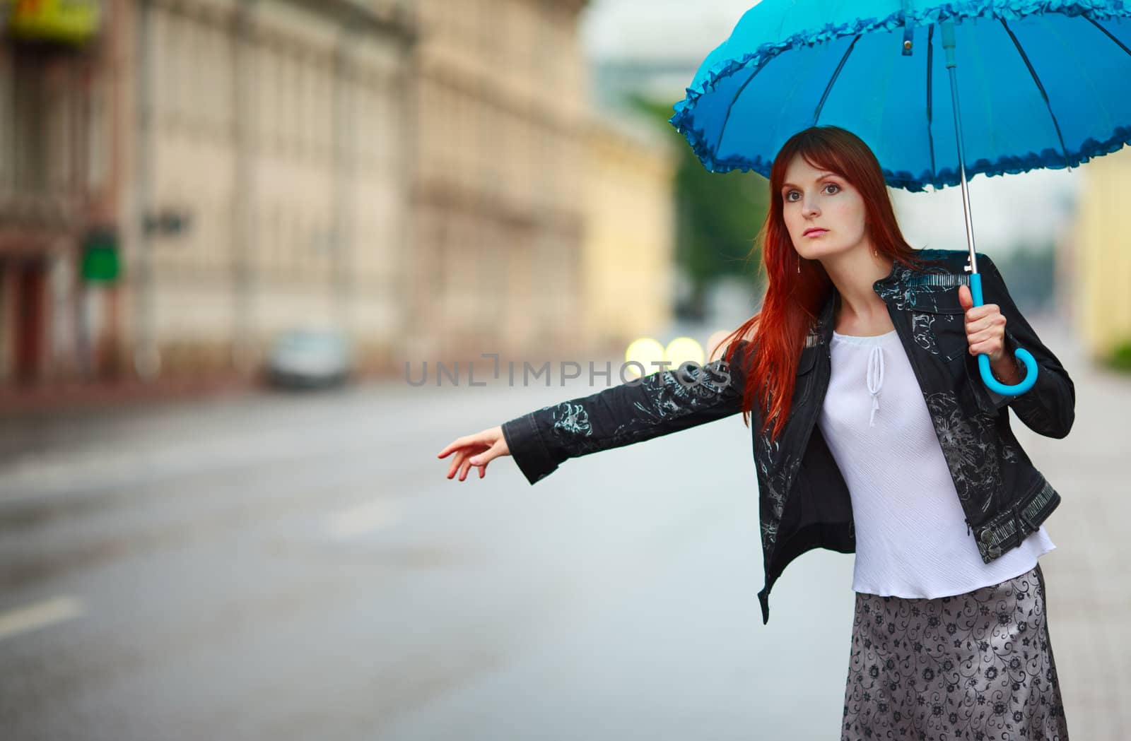 redhead girls with umbrella hitch-hiking at rainy day