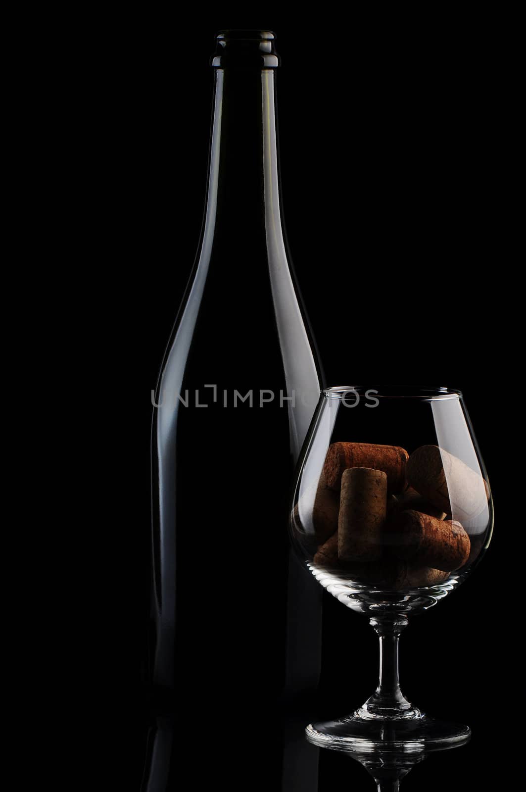 Cork in a glass and wine bottle on black background
