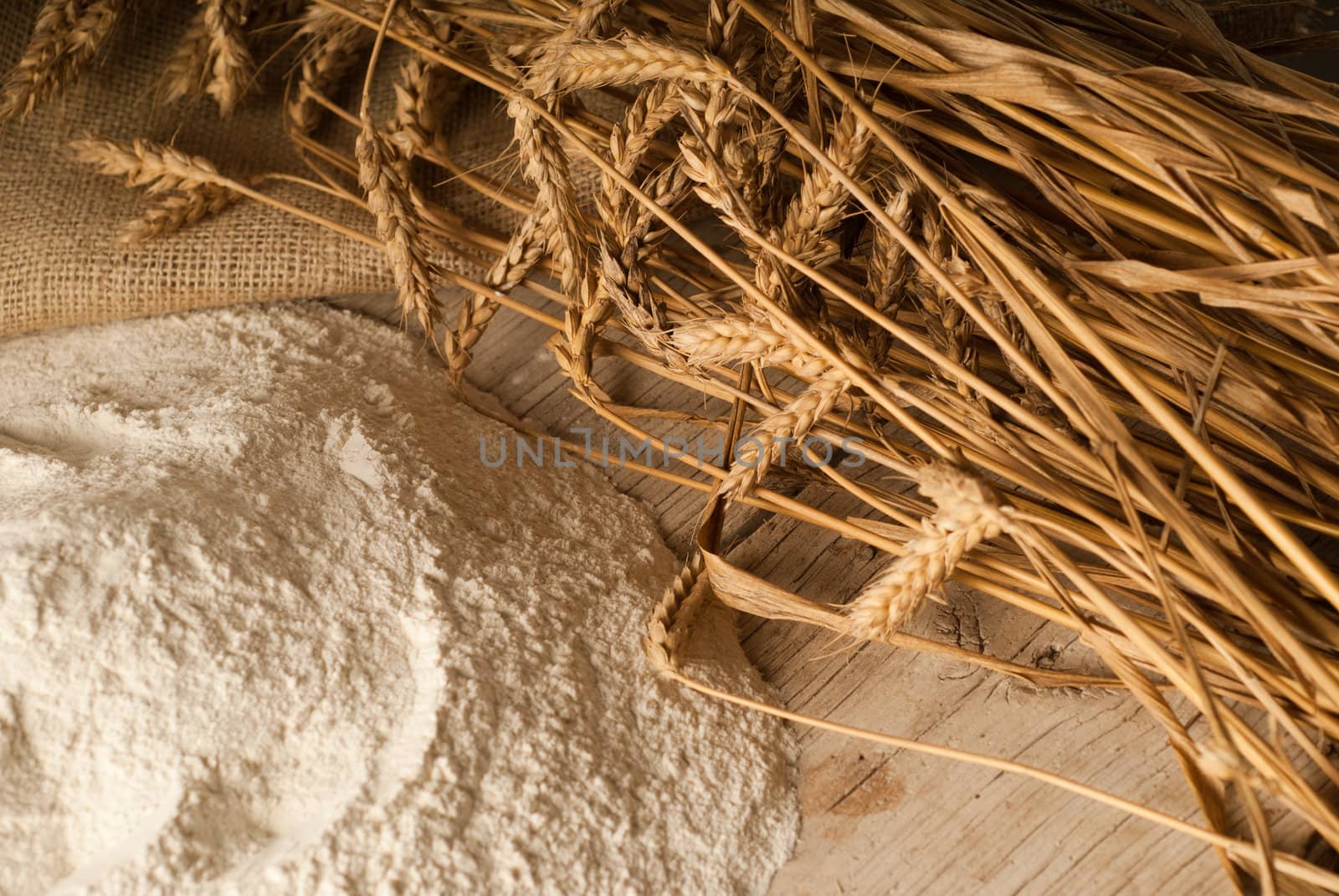 Flour powder on a wooden table garnished with wheat