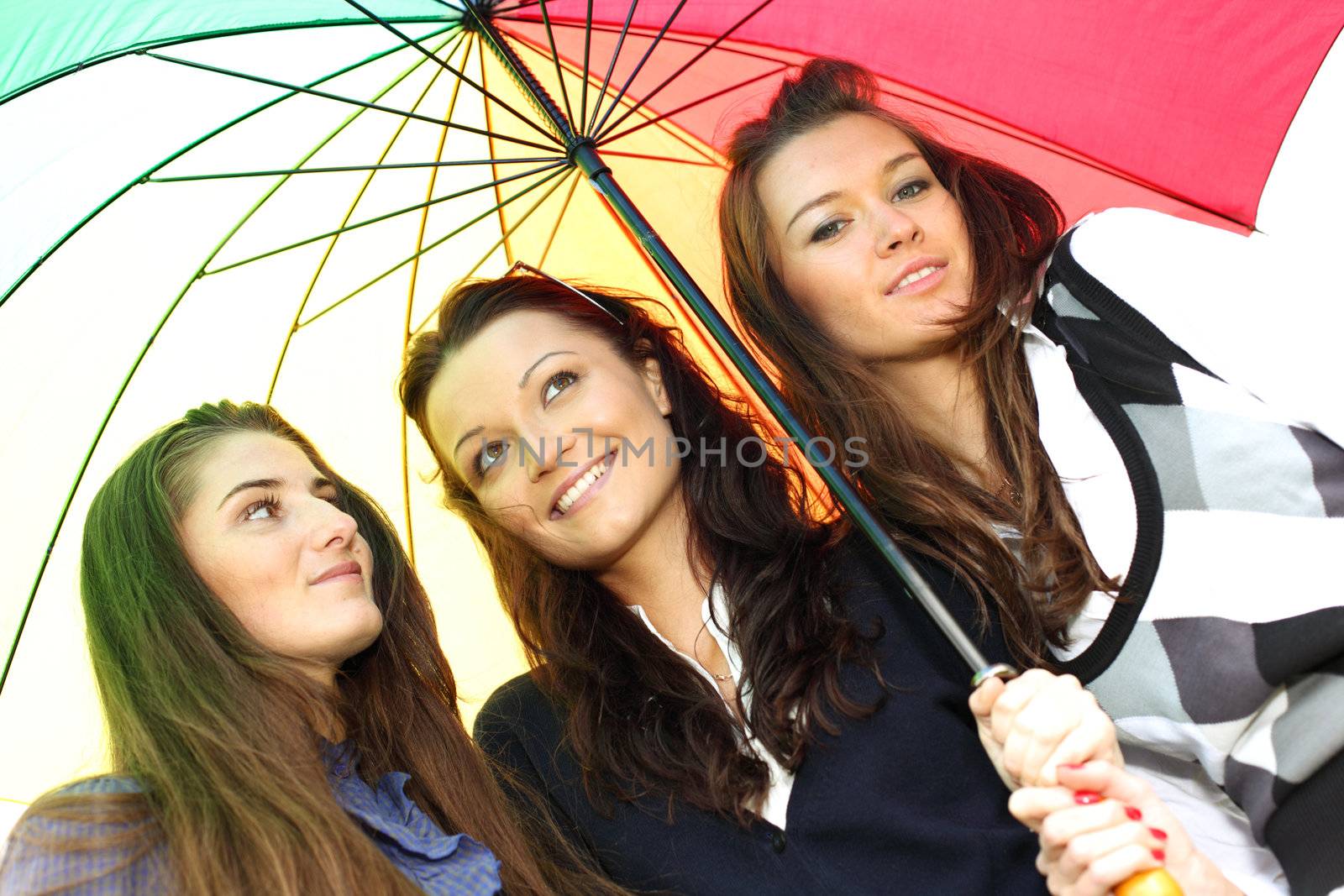 happy smiling girlfriends stay under colourful umbrella  