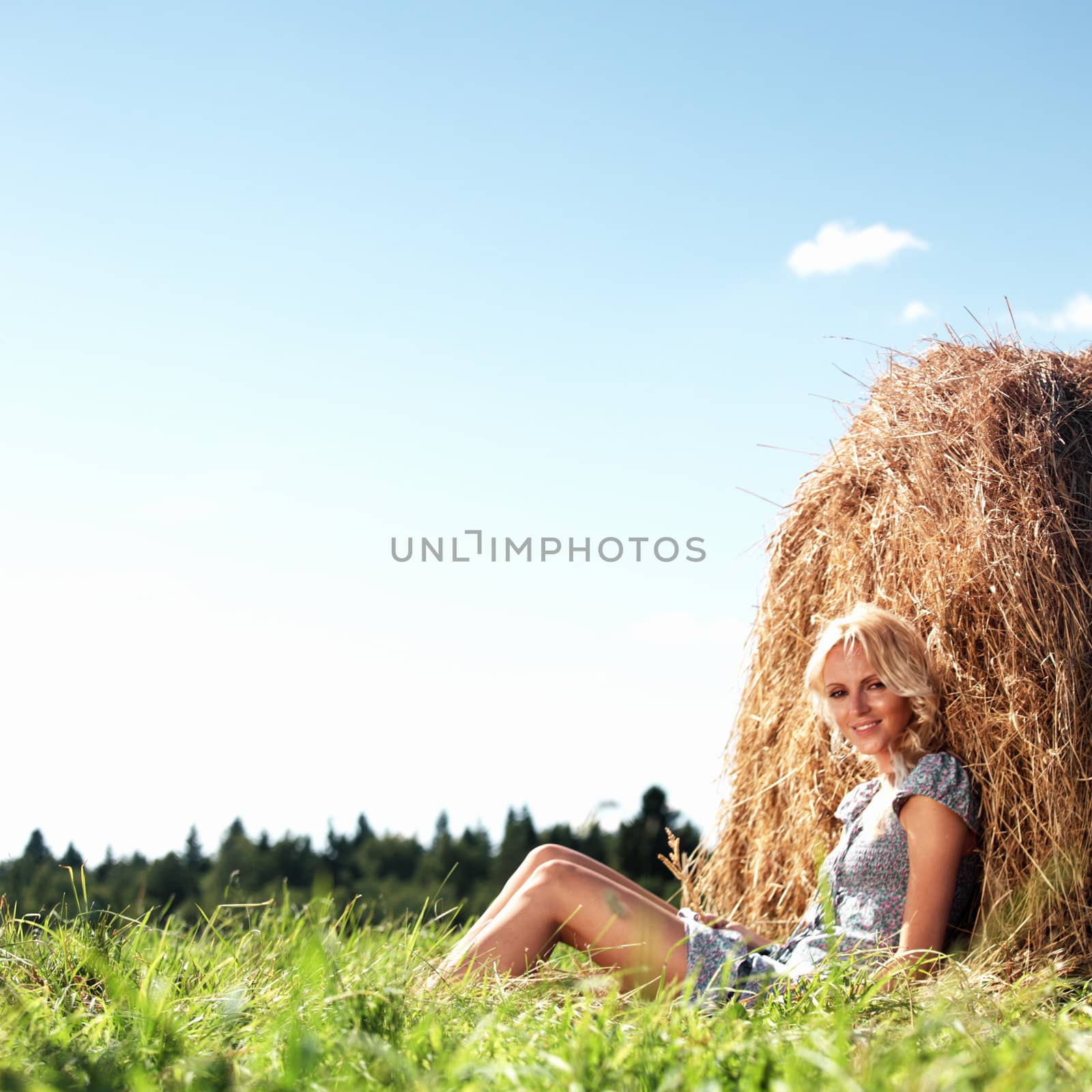 portrait of a girl next to a stack of hay under the blue sky