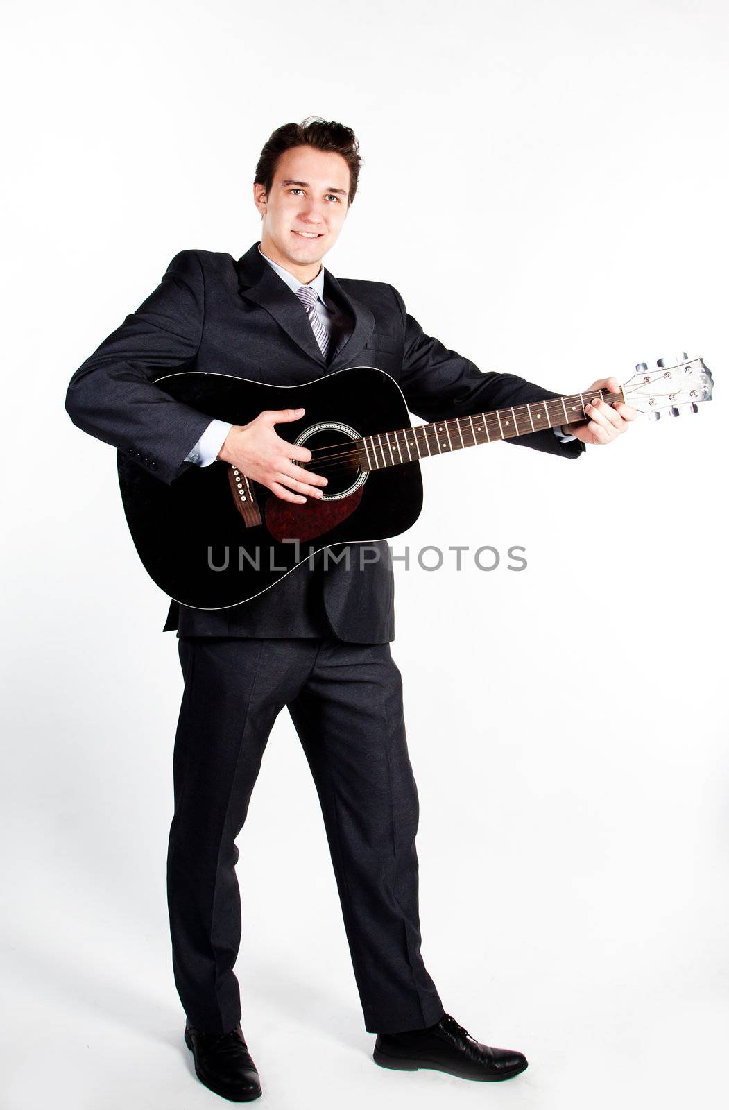 Young handsome man in a dark business suit, sings and plays guitar