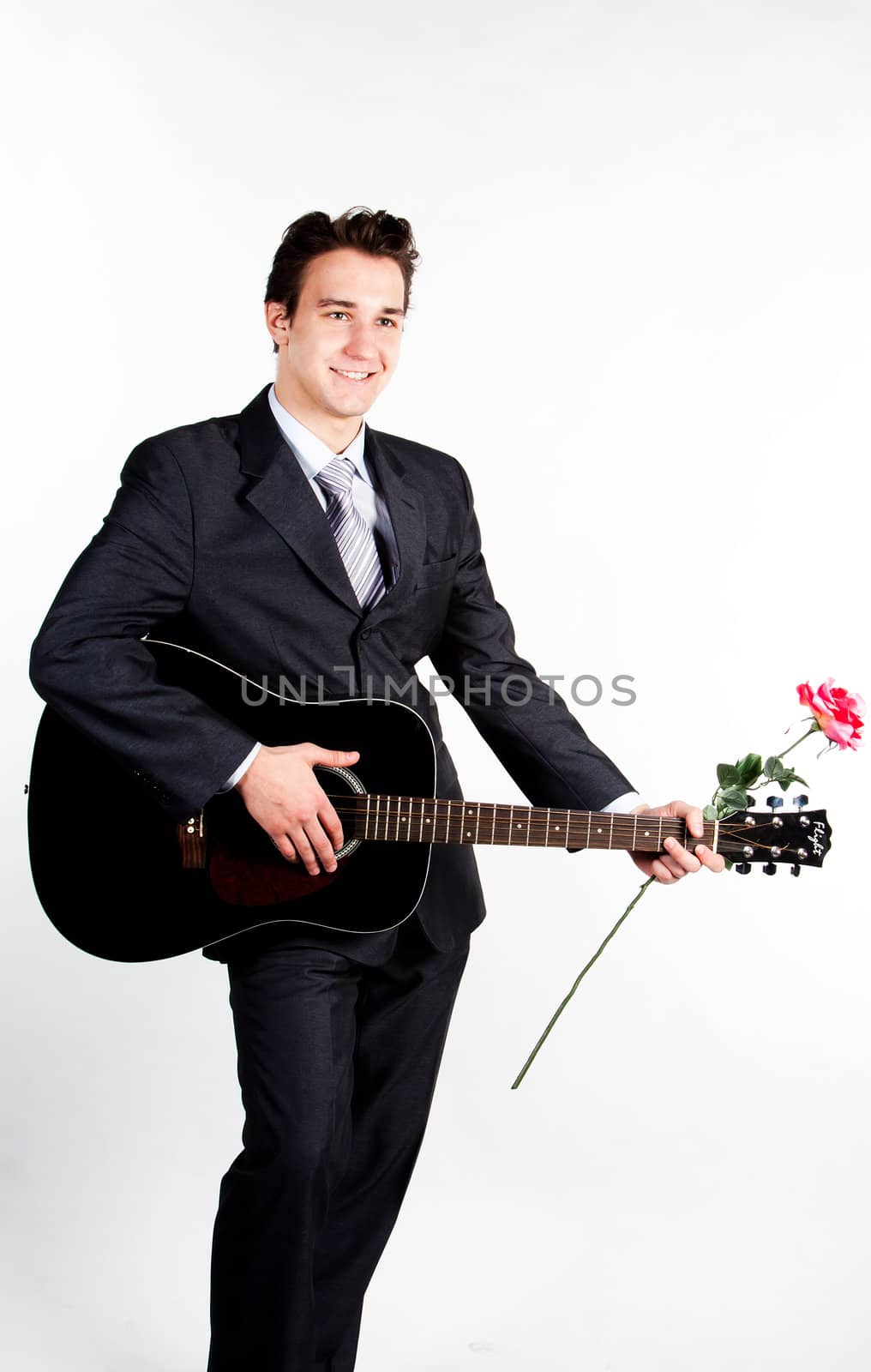 Young handsome man in a dark business suit, sings and plays guitar