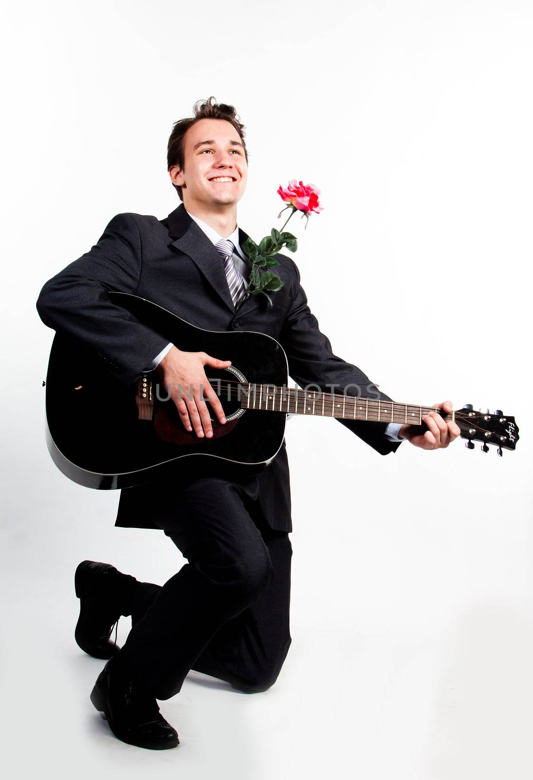 Young handsome man in a dark business suit, sings and plays guitar