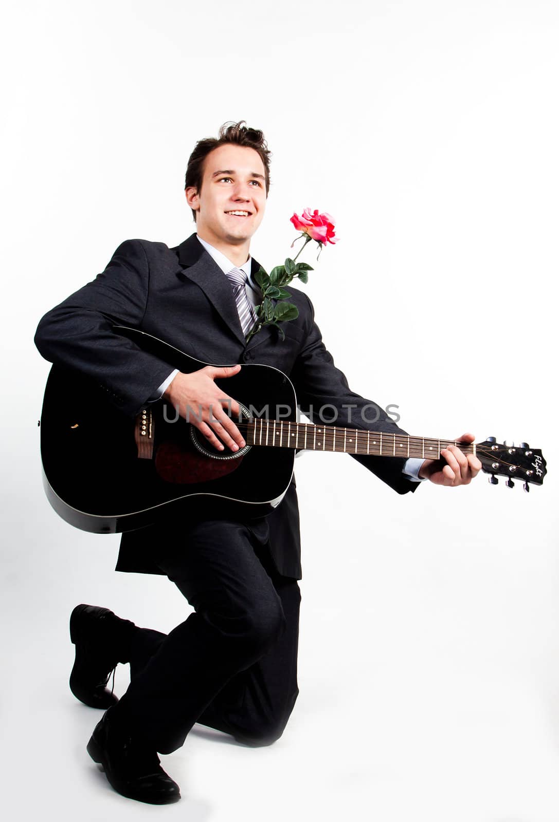 Young handsome man in a dark business suit, sings and plays guitar