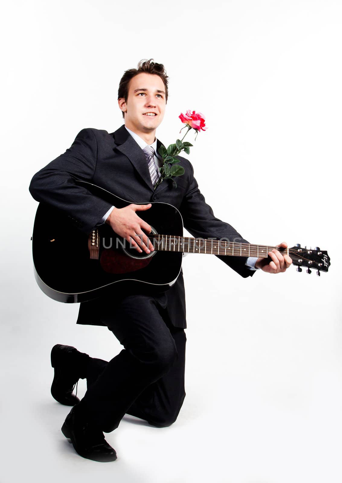 Young handsome man in a dark business suit, sings and plays guitar