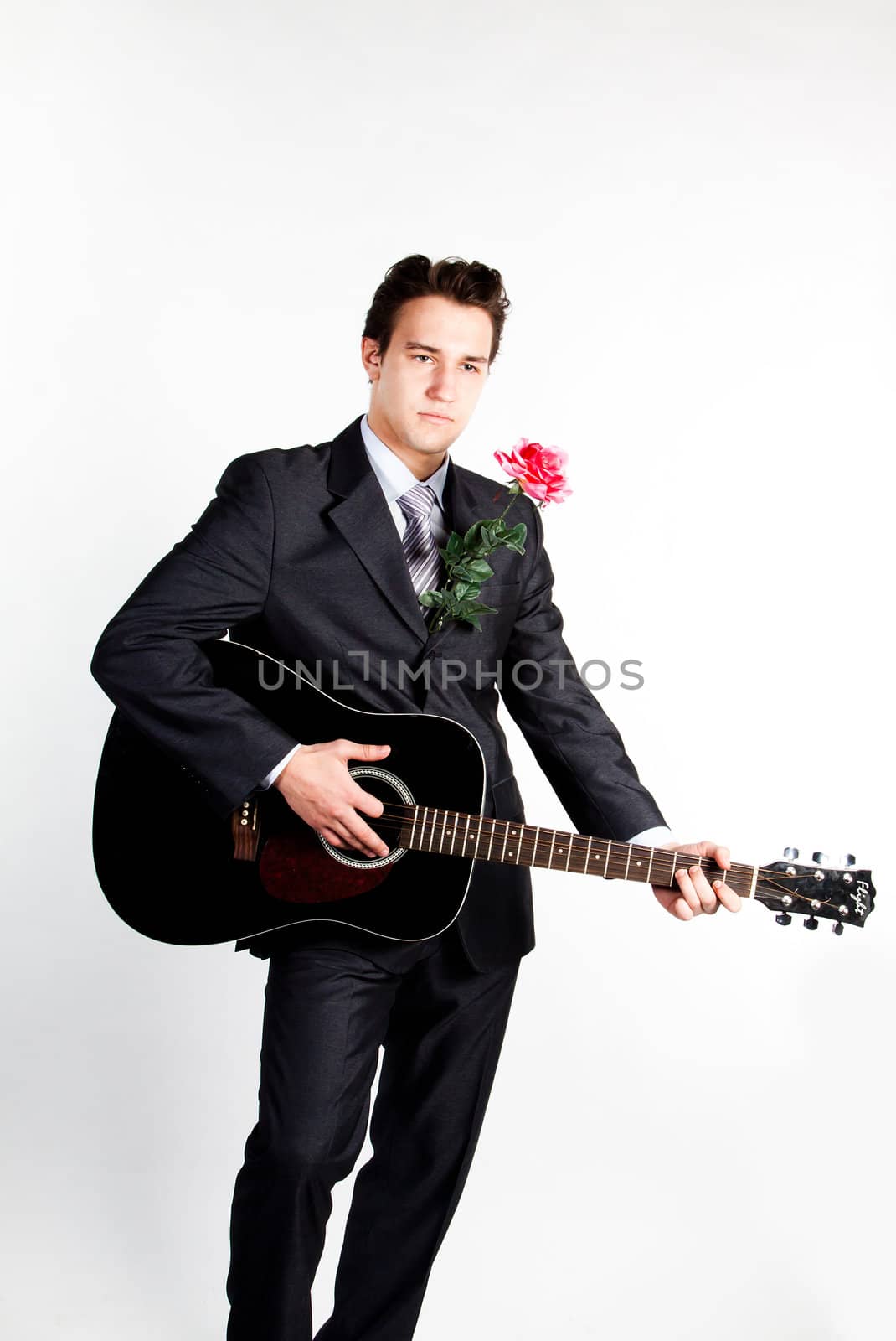 Young handsome man in a dark business suit, sings and plays guitar
