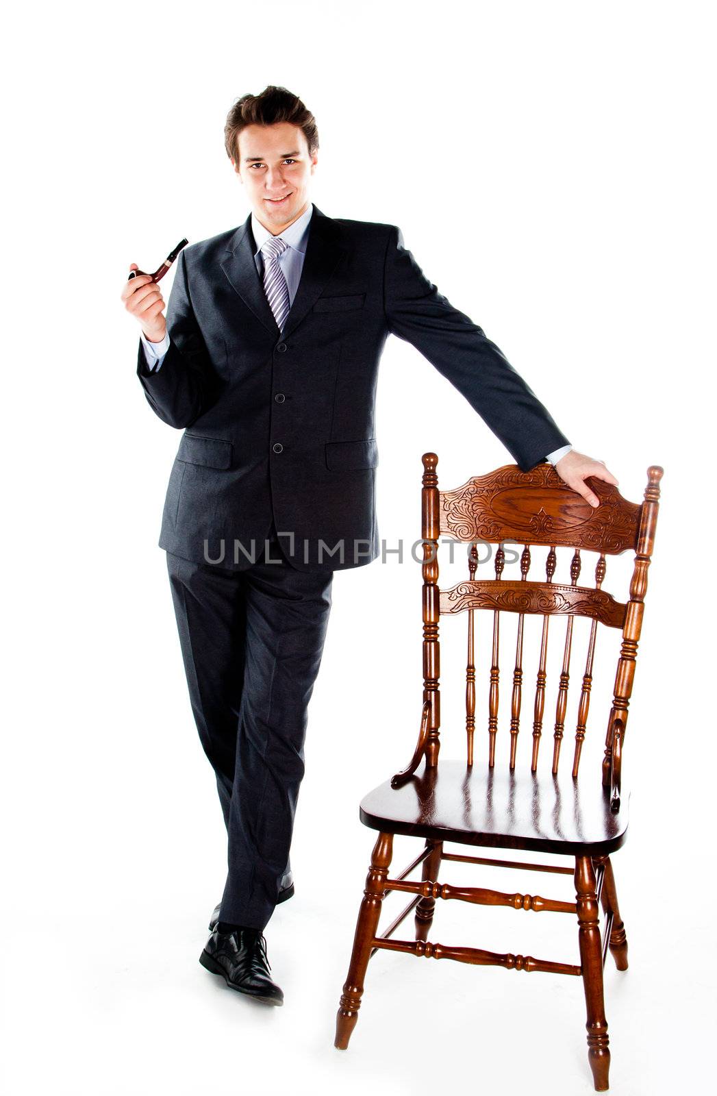 Portrait of a young handsome man in a dark suit with a strict smoking a pipe in his hand