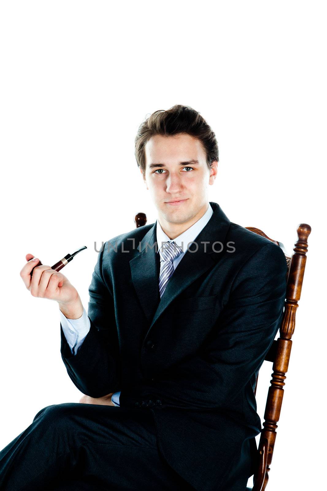 Portrait of a young handsome man in a dark suit with a strict smoking a pipe in his hand