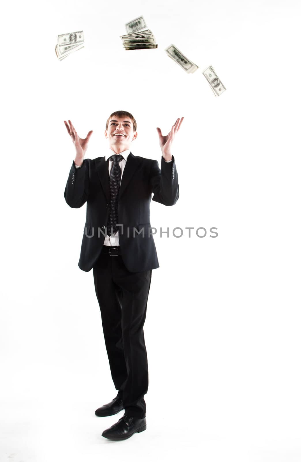 Portrait of a young businessman in a dark suit surrounded by flying dollar bills