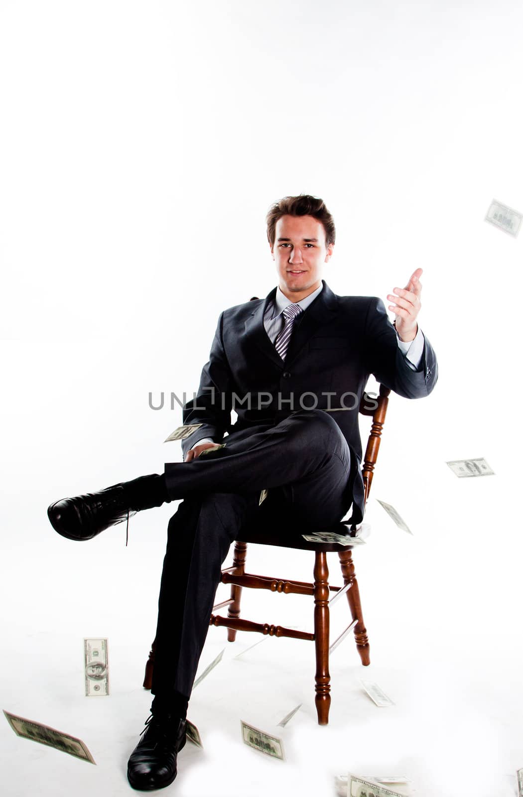 Portrait of a young businessman in a dark suit surrounded by flying dollar bills