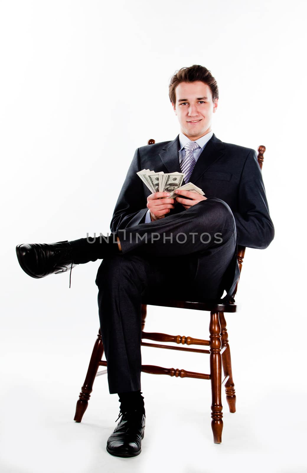Portrait of a young businessman in a dark suit surrounded by flying dollar bills