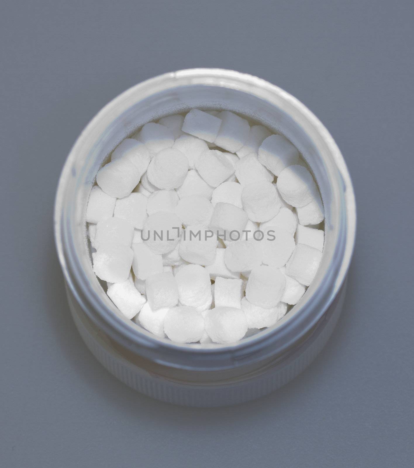 Barrell of little white pills over gray background