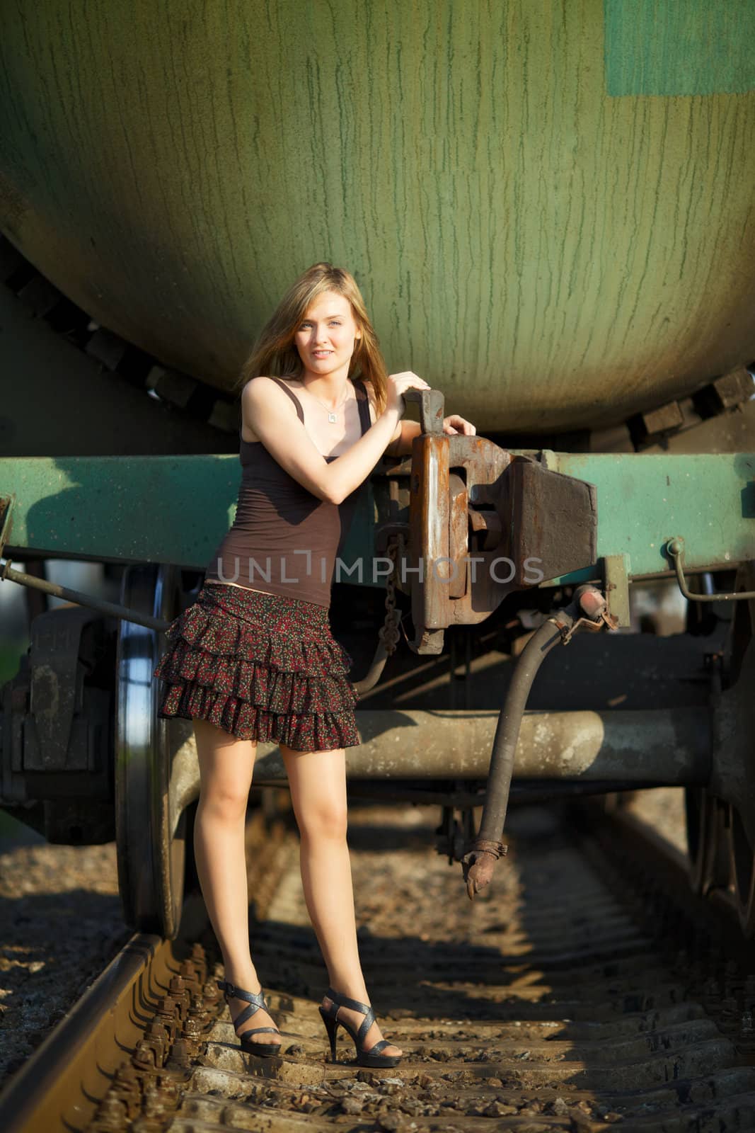 beautiful girl standing on rails near railroad car