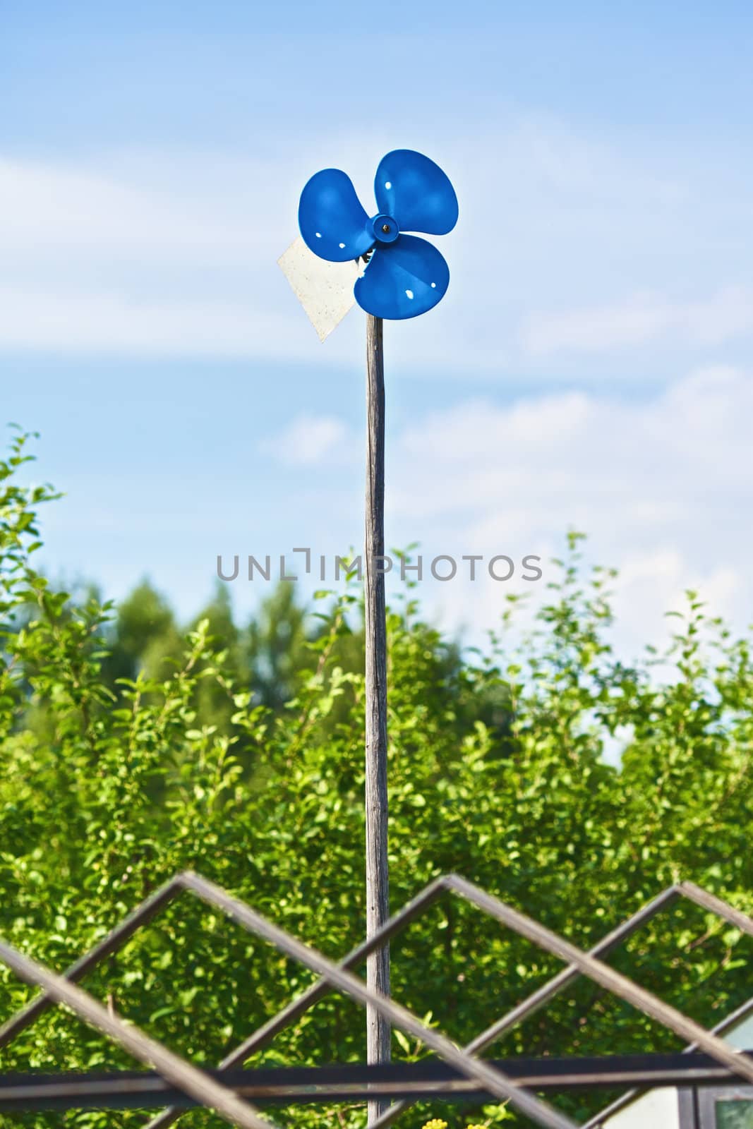 blue garden windmill against cloudy sky at summer day