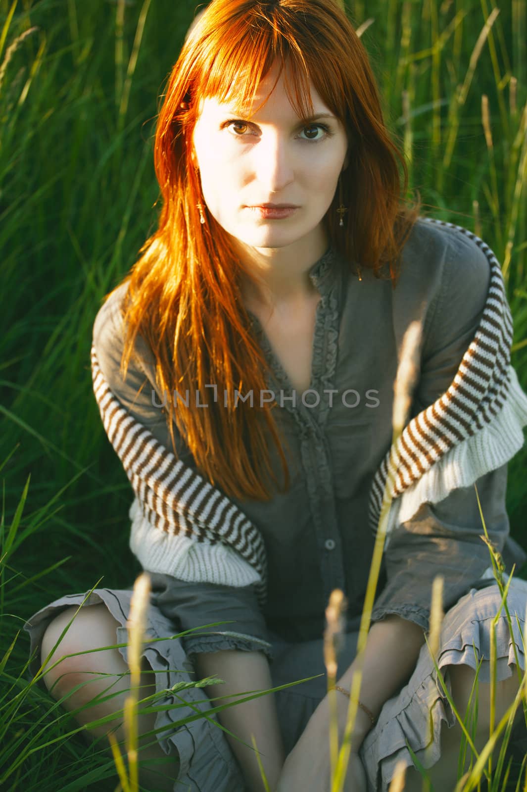 sad woman sitting in field at summer day