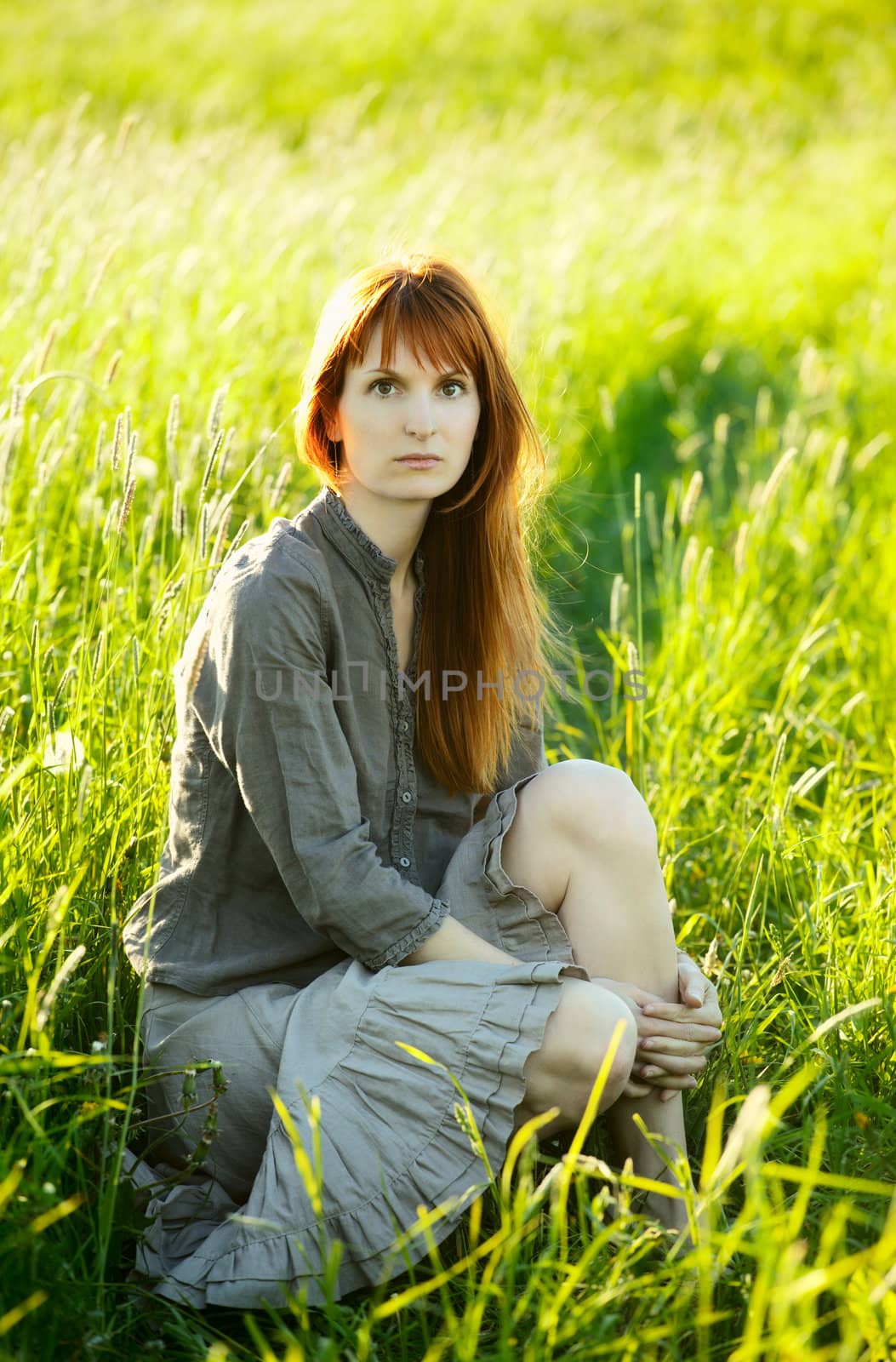 sad woman sitting in field at summer day