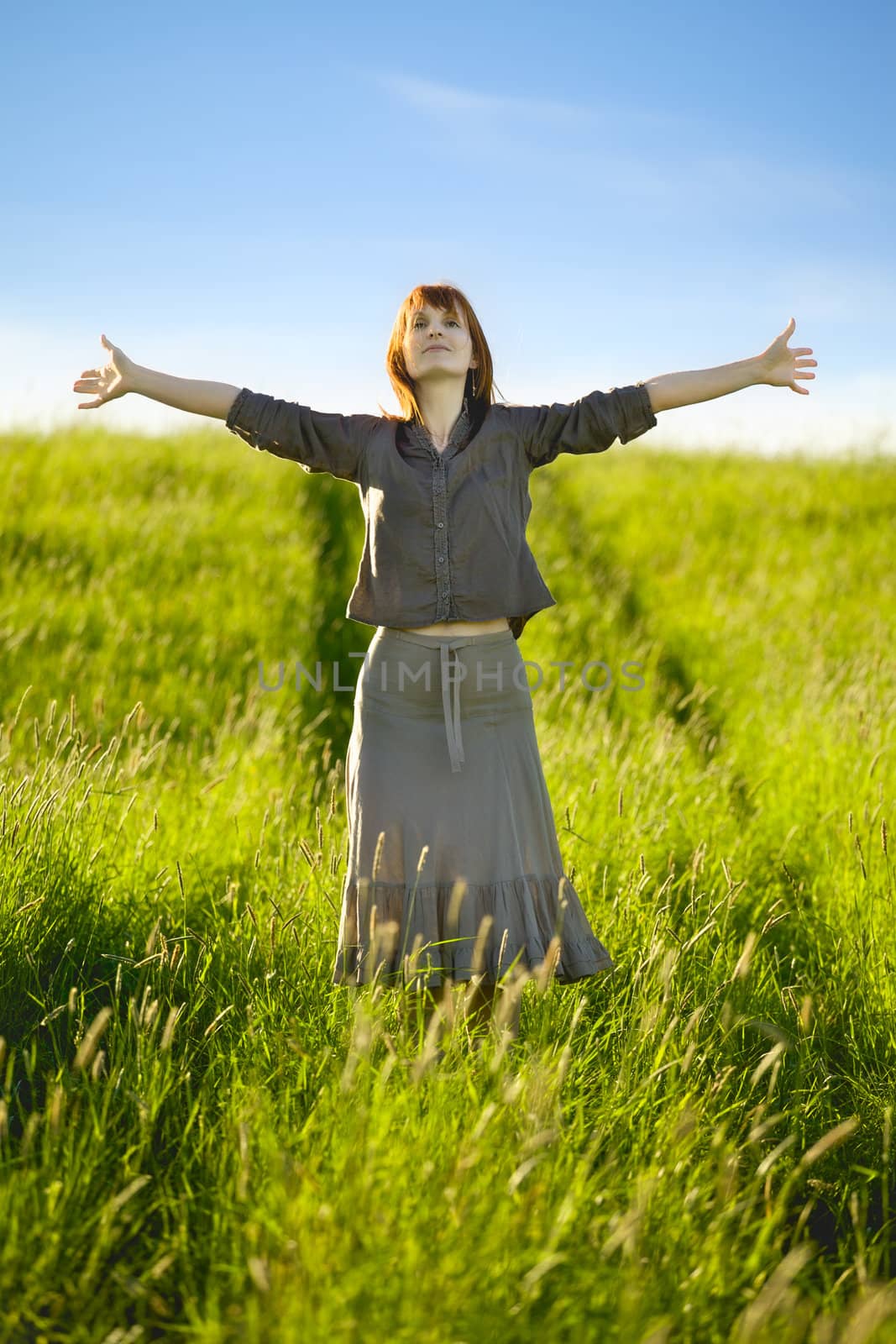 happy woman with open arms in field at summer day