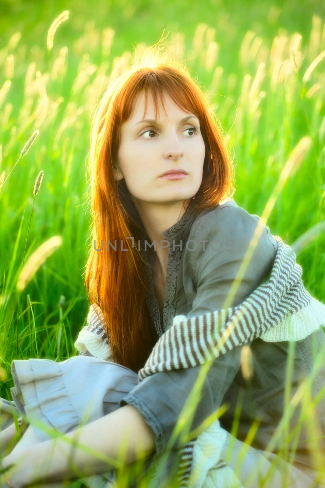 sad woman sitting in field at summer day