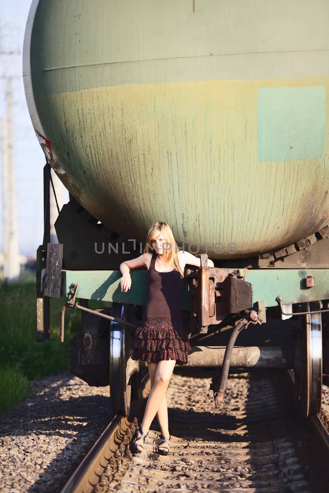 beautiful girl standing on rails near railroad car