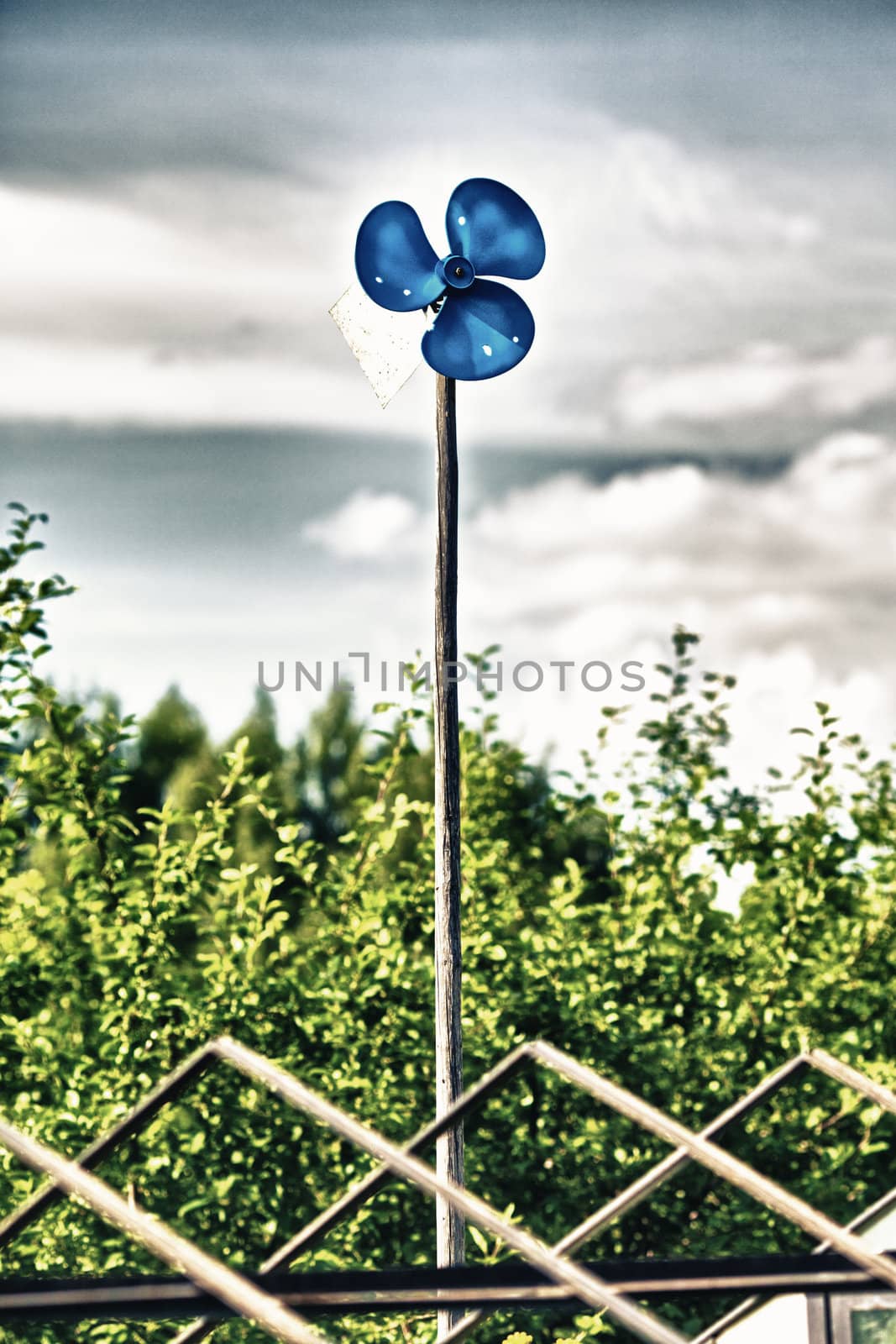 blue garden windmill against cloudy sky at summer day