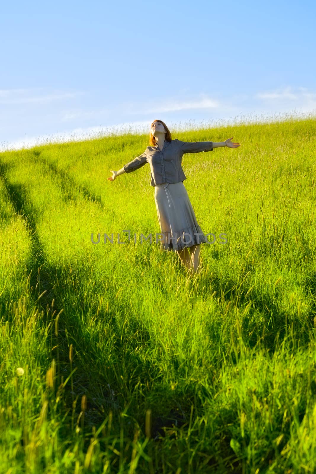 happy woman with open arms in field at summer day