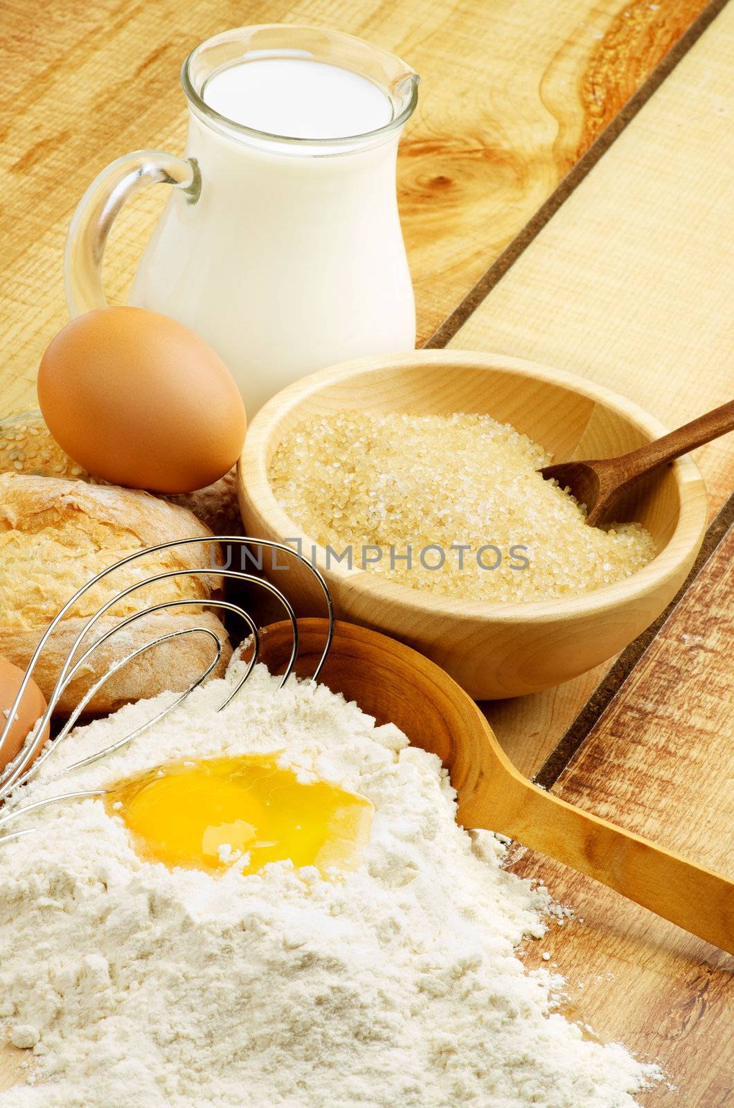 Preparing Dough. Ingredients with Jar of Milk, Flour, Egg, Sugar and Wooden Spoon with Egg Whisk closeup on Wooden background