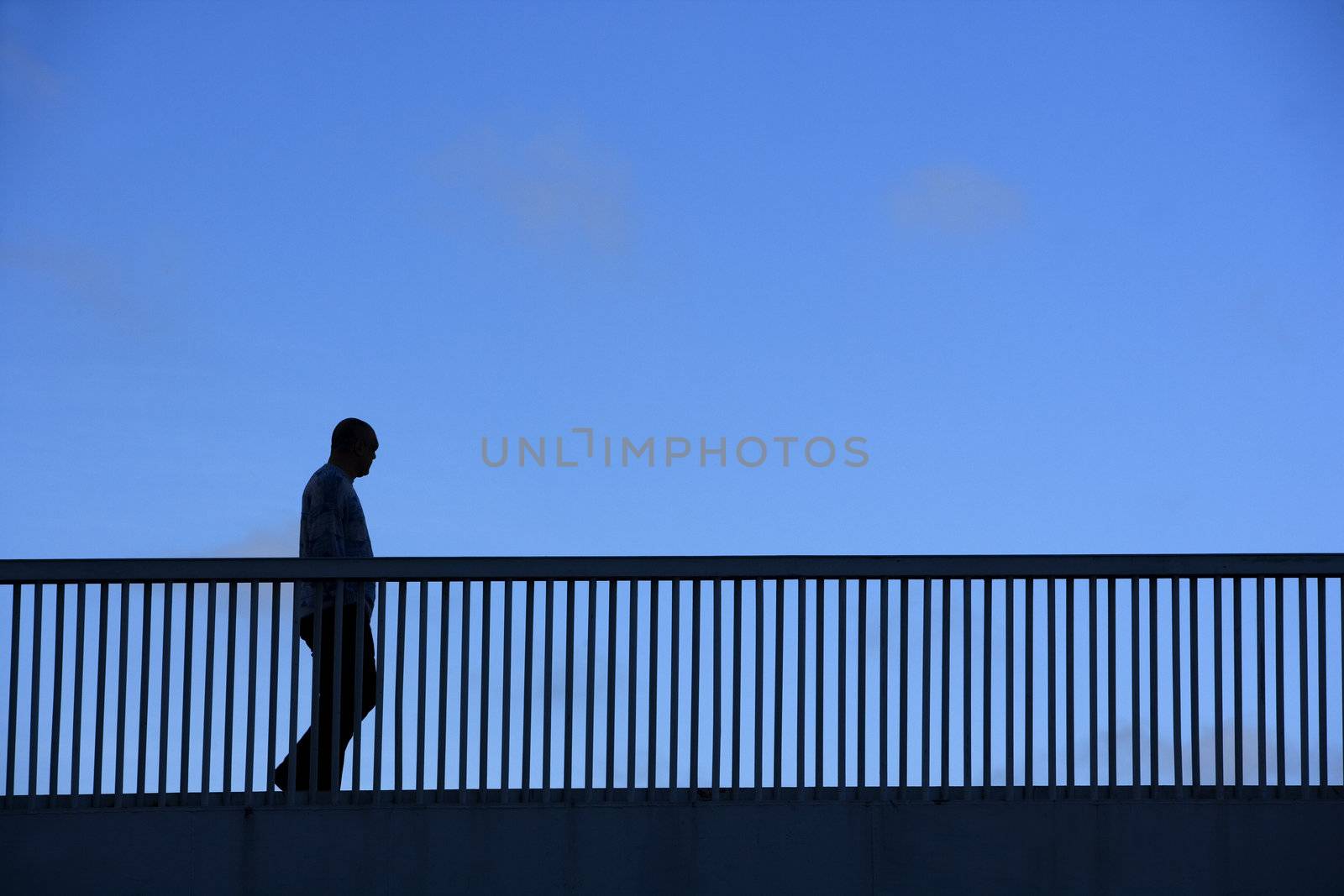 Silhouette of a walking man on a bridge