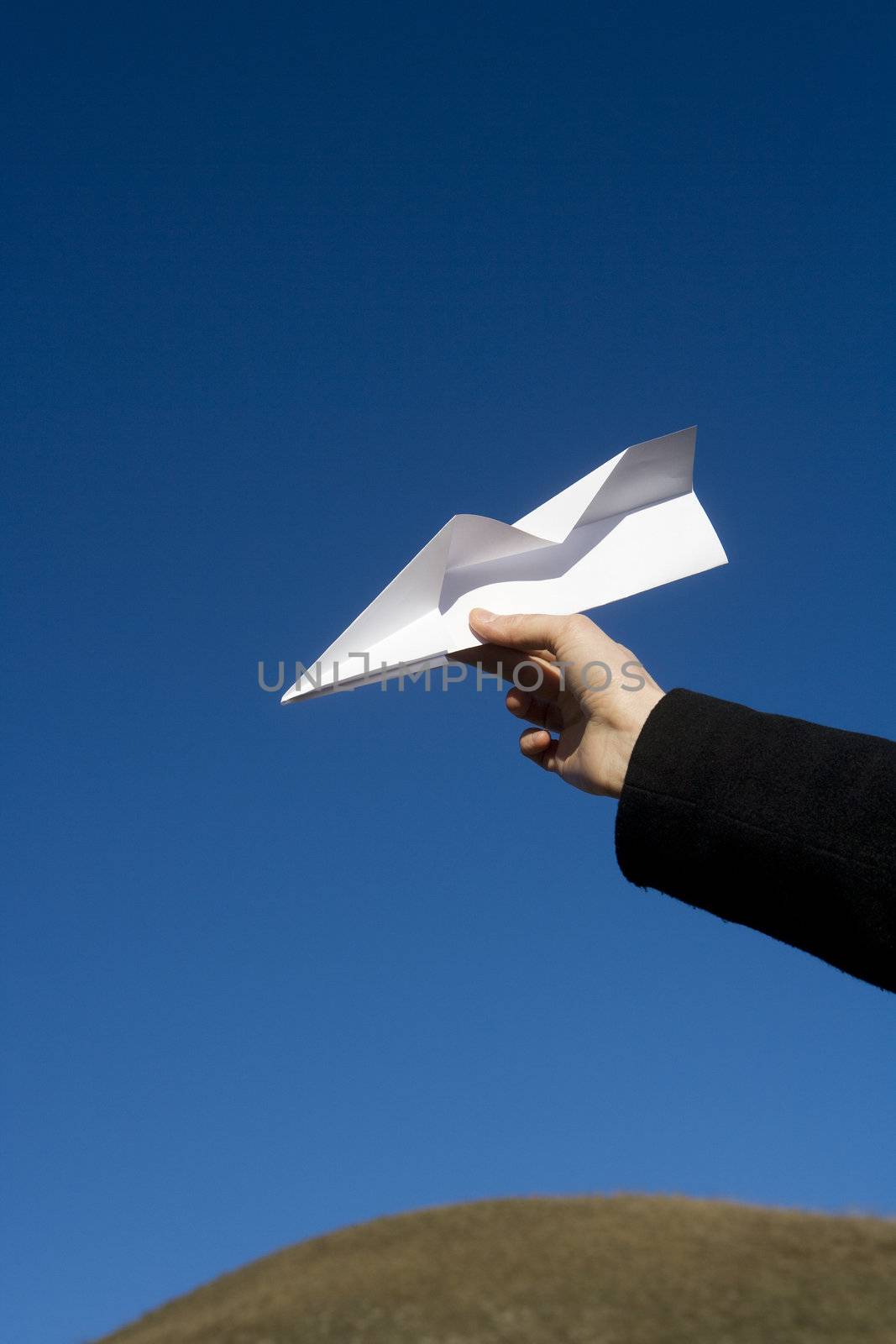 Hand holding a Paper Airplane towards blue sky