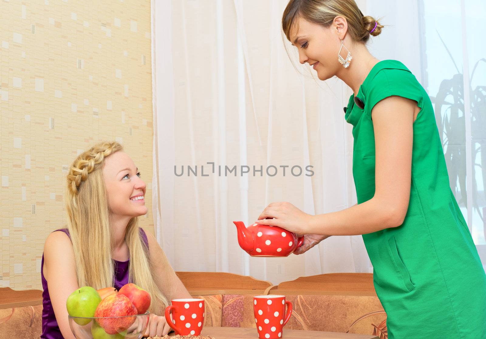 two young woman sitting at a table having tea