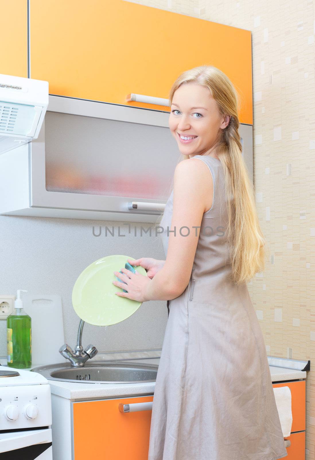 beautiful blond girl washing dishes at kitchen