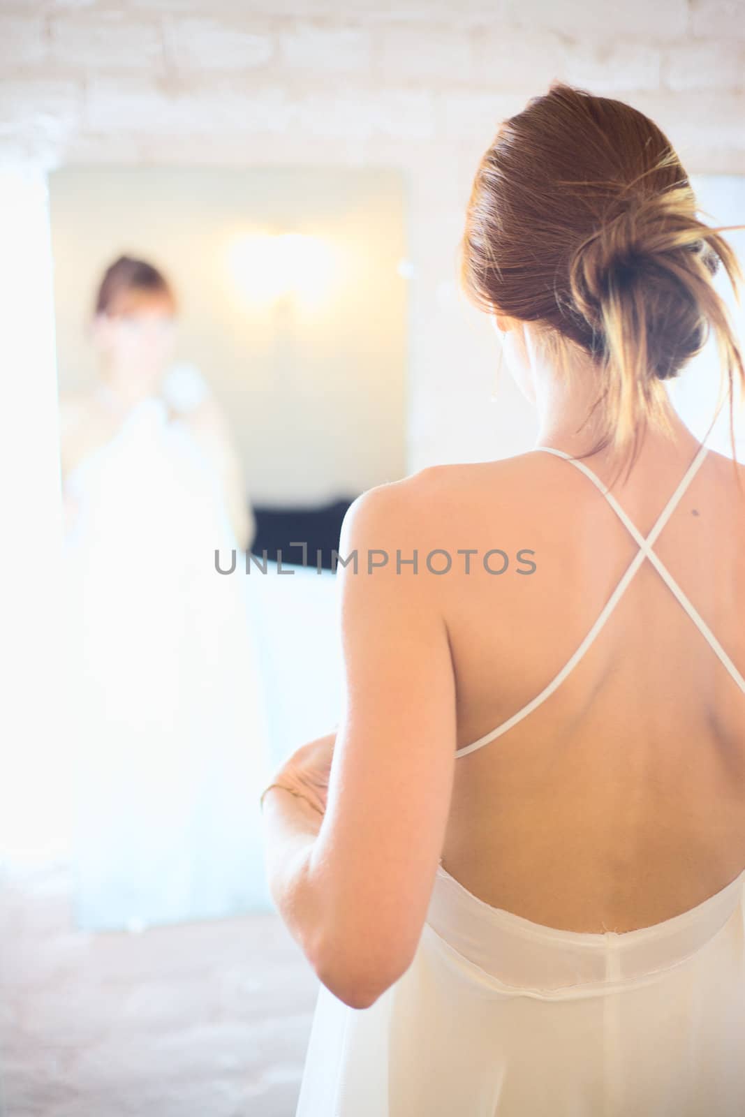 beautiful woman in white wedding dress in front of mirror