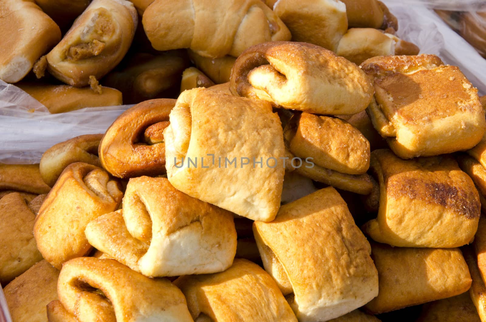 Baked homemade sweet buns with cinnamon sold in outdoor street market fair sunlit.