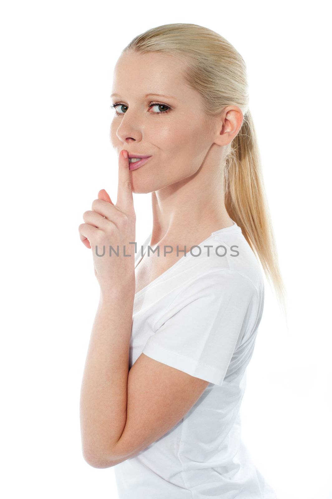 Side view of pretty smiling girl with finger on her lips against white background